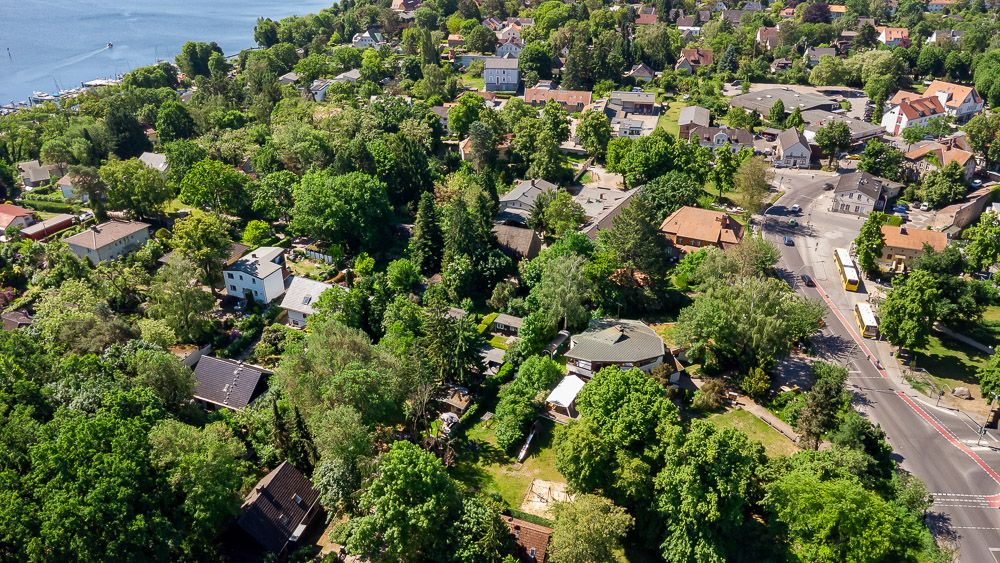 Luftaufnahme eines Wohngebiets mit vielen Bäumen und Häusern, nahe einem See.
