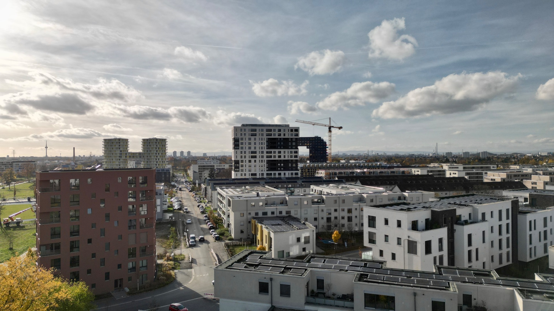 Blick auf ein Wohngebiet mit modernen Mehrfamilienhäusern und Straßen bei bewölktem Himmel.