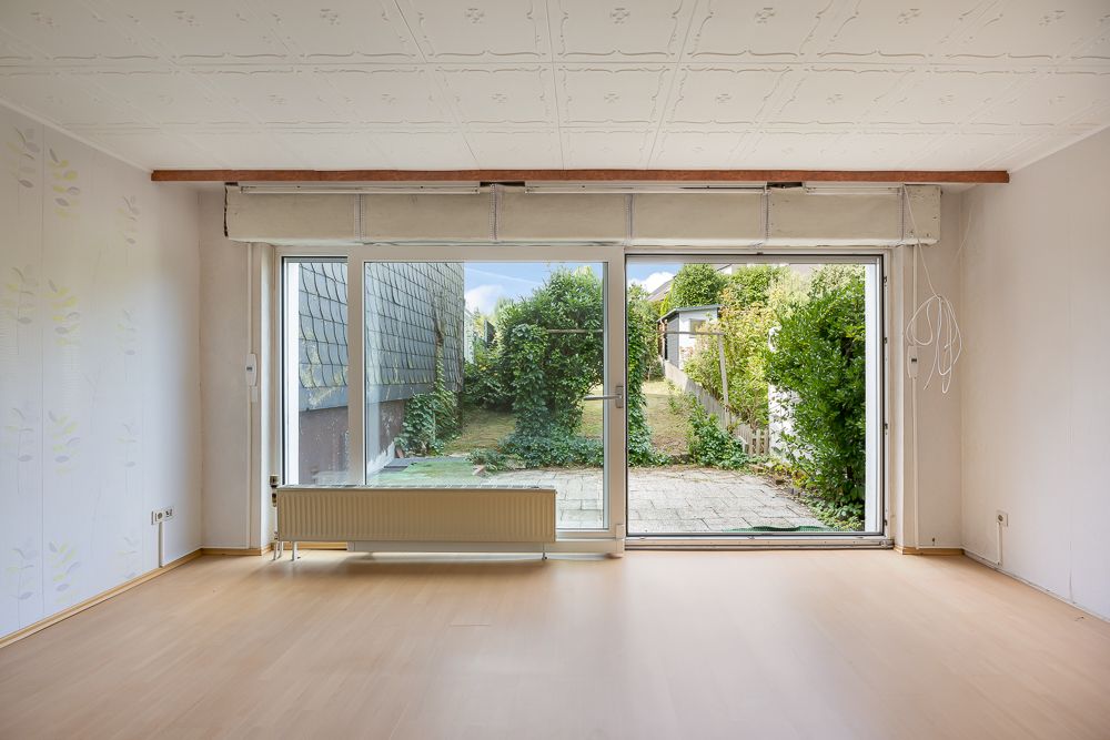 Helles Wohnzimmer mit Parkettboden und großen Fenstern zur Terrasse und Garten.