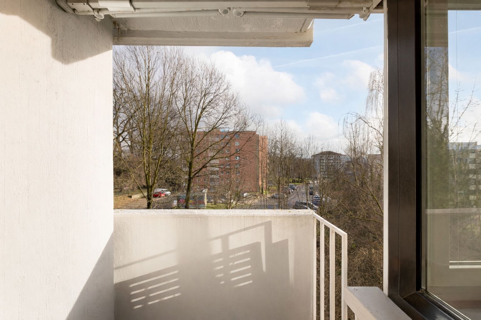 Balkon mit Blick auf Bäume und Wohngebäude im Hintergrund.