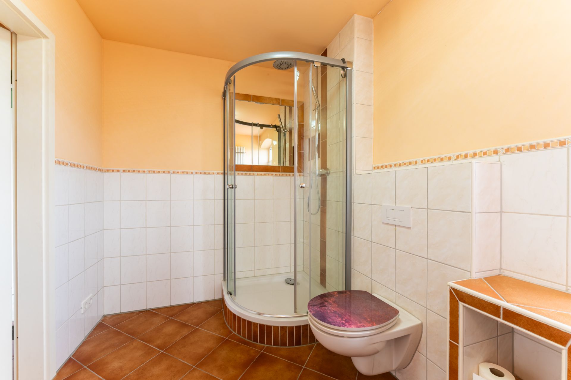 Helles Bad mit Eckdusche, wandhängender Toilette und gefliestem Boden.