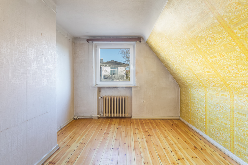 Leerer Raum mit Holzfußboden, einem Fenster und einer gelb gemusterten Schräge.