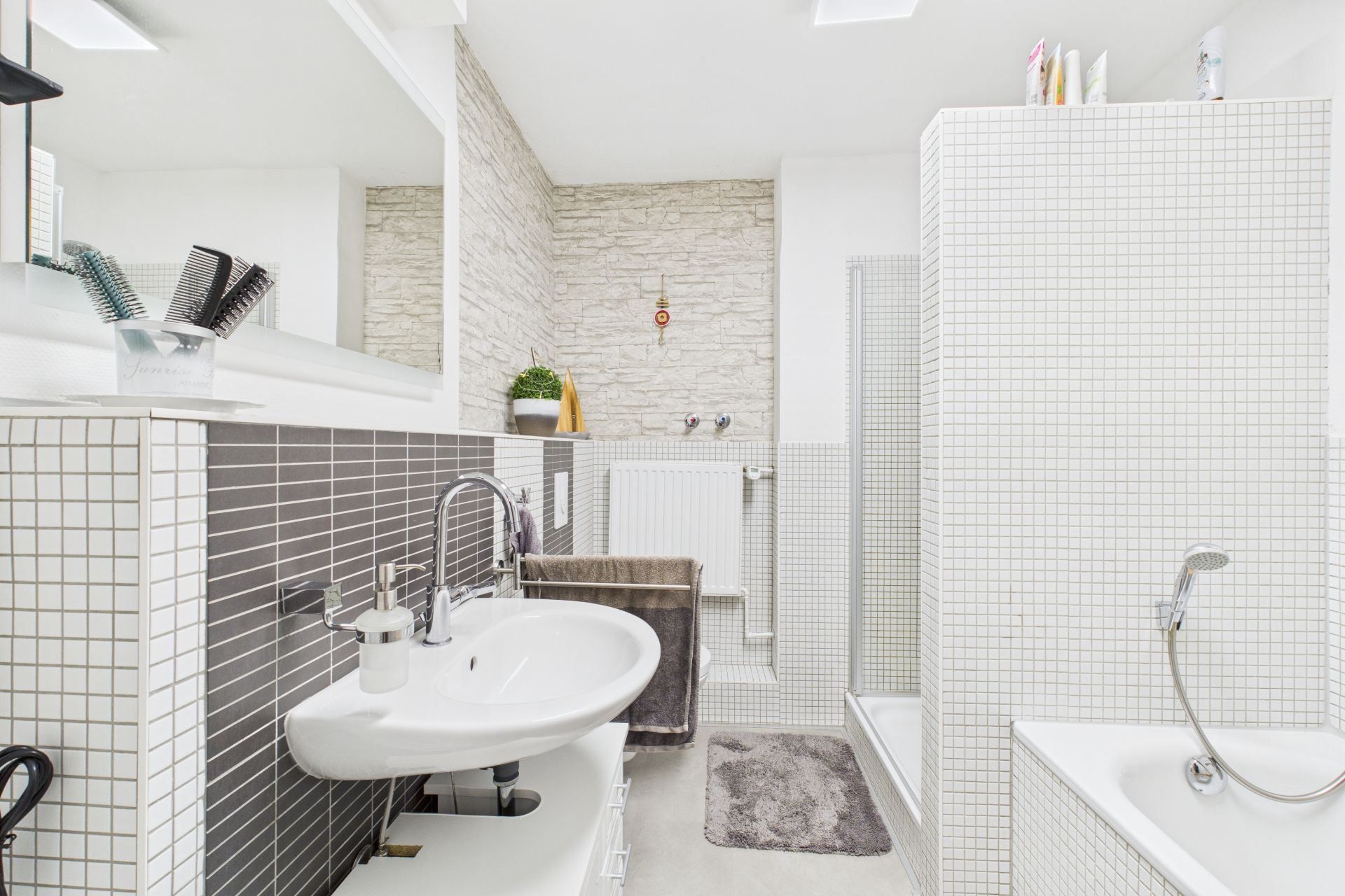 Modernes Badezimmer mit Waschbecken, Dusche, Badewanne und weiß gefliesten Wänden.