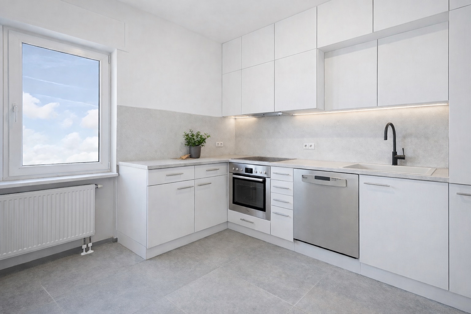 Moderne, helle Küche mit weißen Schränken, Einbauherden und großem Fenster.
