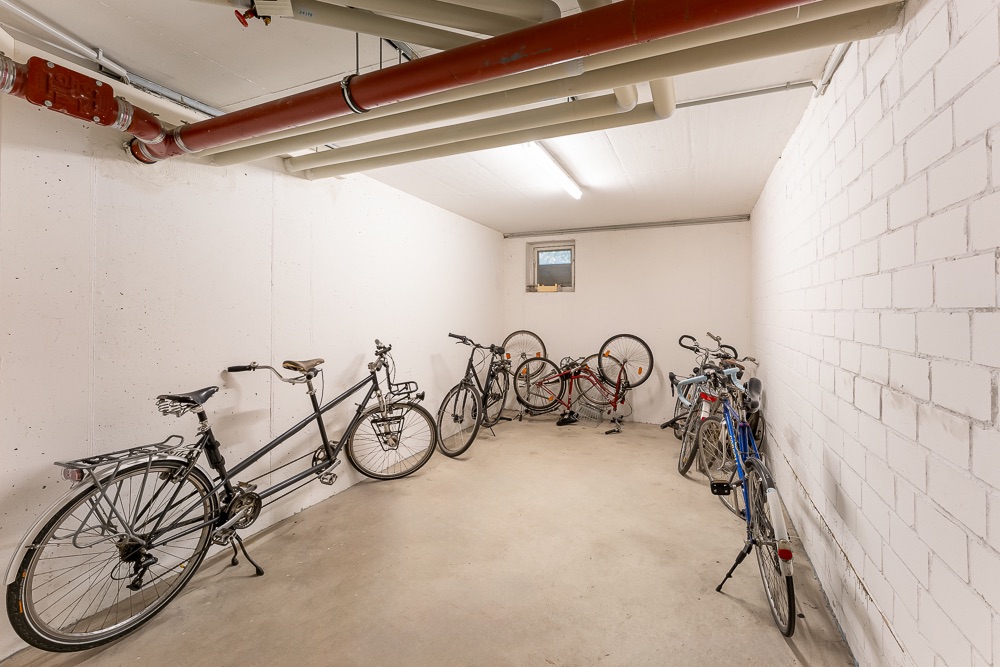 Kellerraum mit mehreren abgestellten Fahrrädern und sichtbaren Rohrleitungen an der Decke.