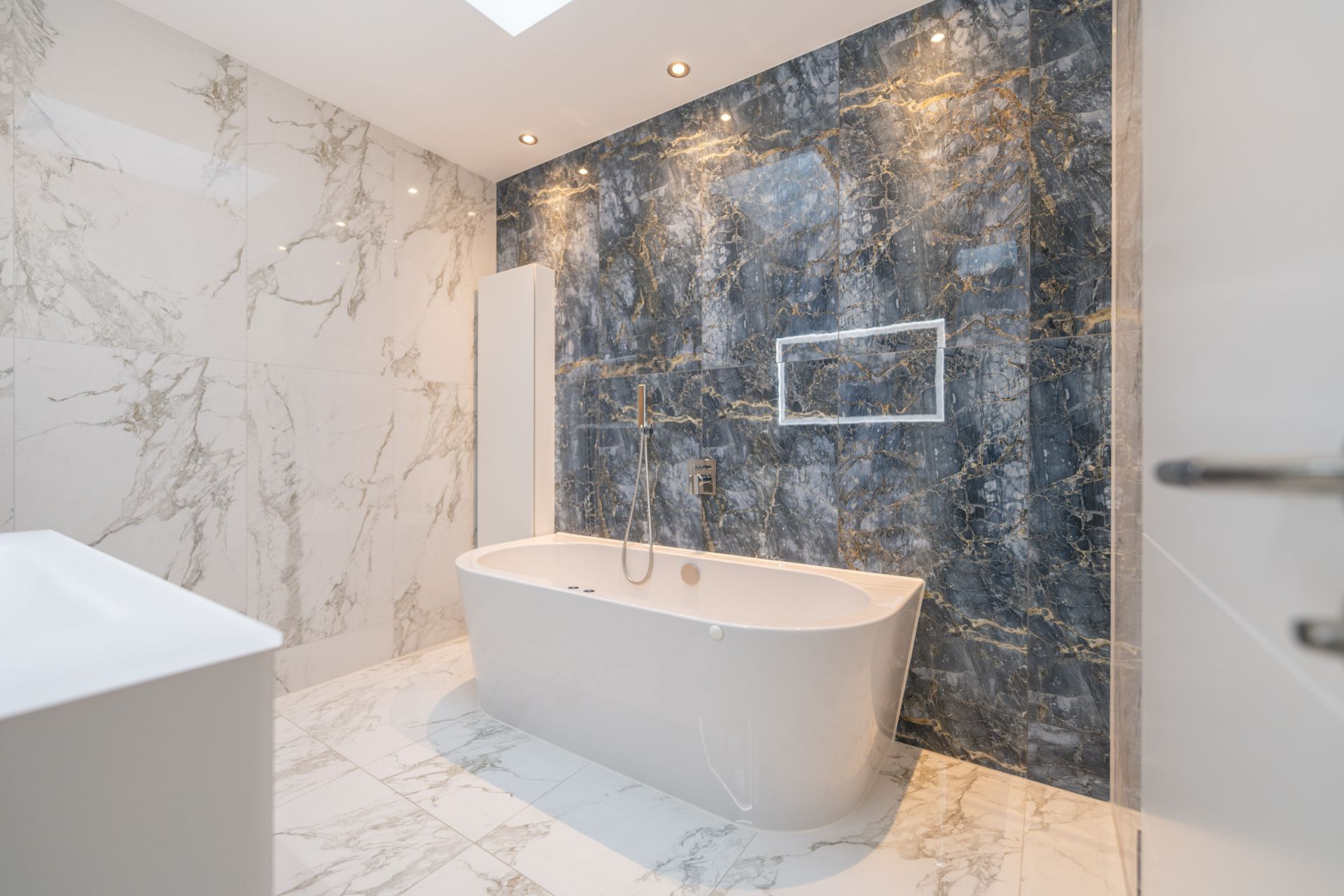 Modernes Bad mit freistehender Badewanne und Marmorfliesen an Wand und Boden.