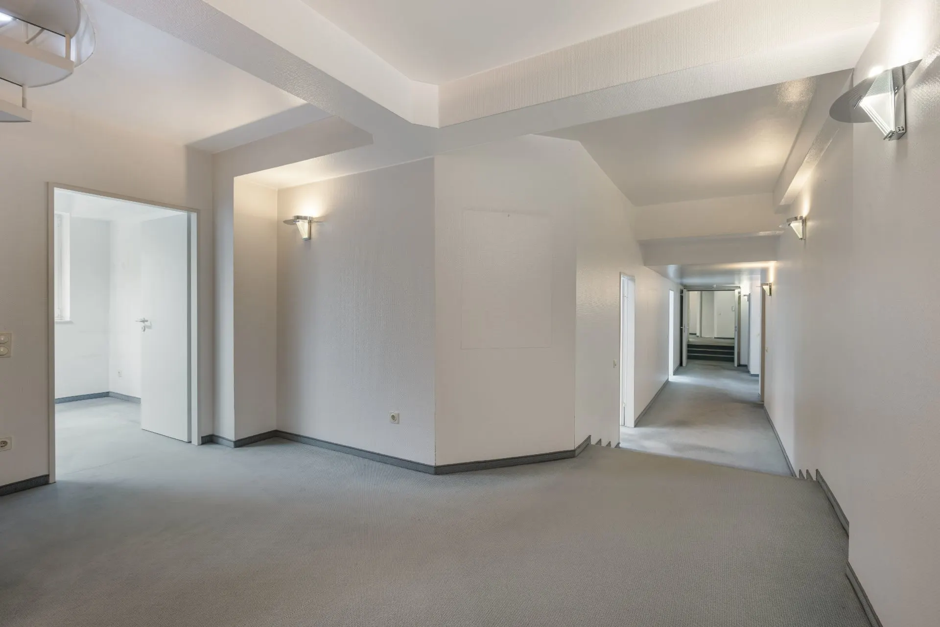 Heller Flur mit grauem Boden und mehreren Türen in einer Wohnung.