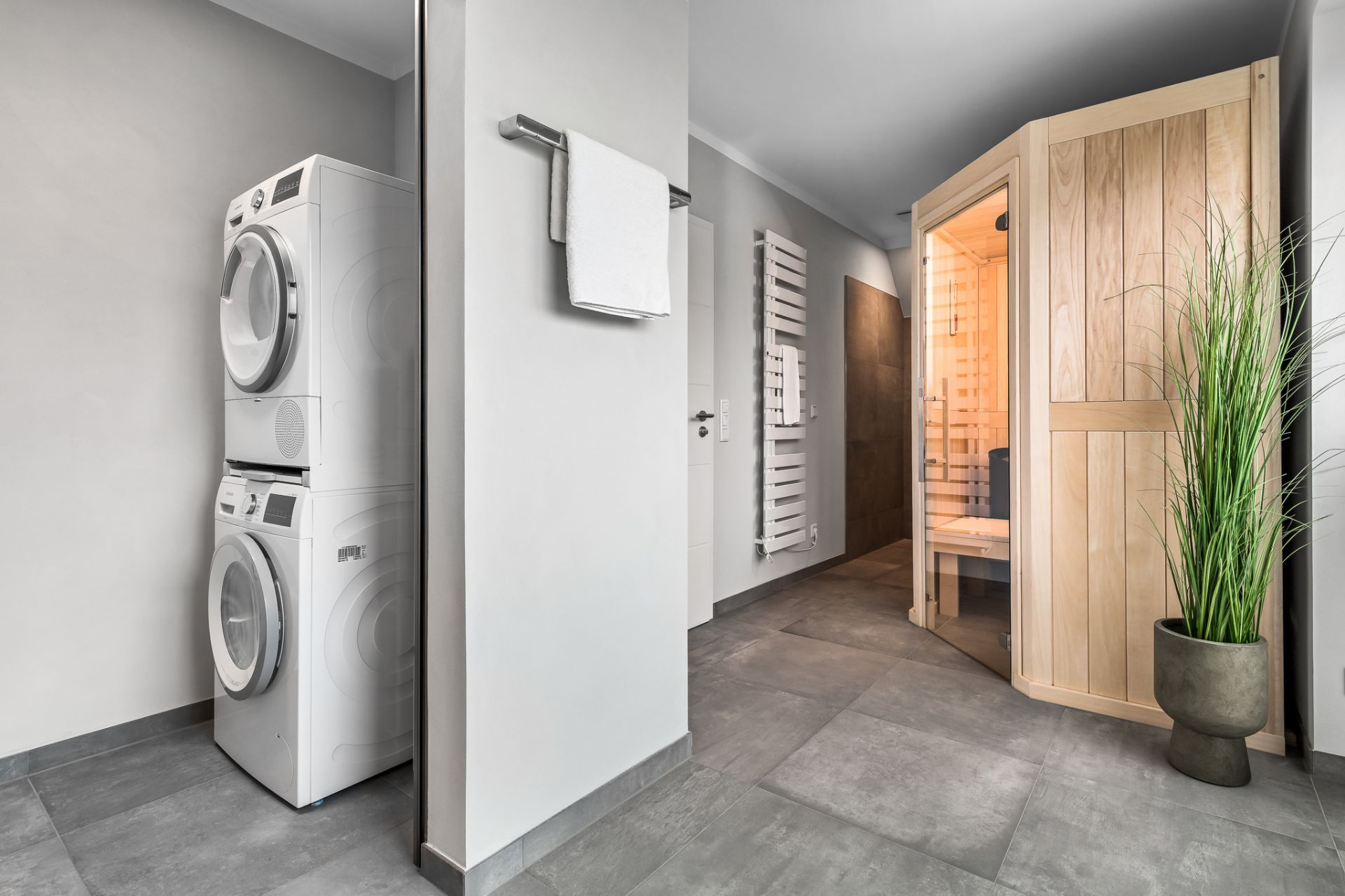 Modernes Badezimmer mit Sauna, Waschmaschine, Trockner und Pflanze im Topf.