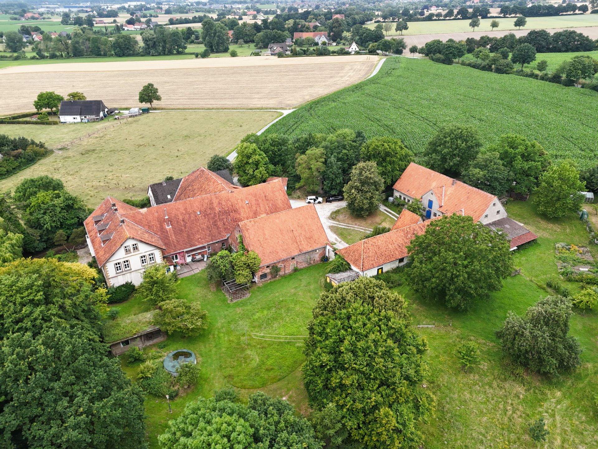 Luftaufnahme eines großen Wohnhauses mit Nebengebäuden und Garten auf dem Land.
