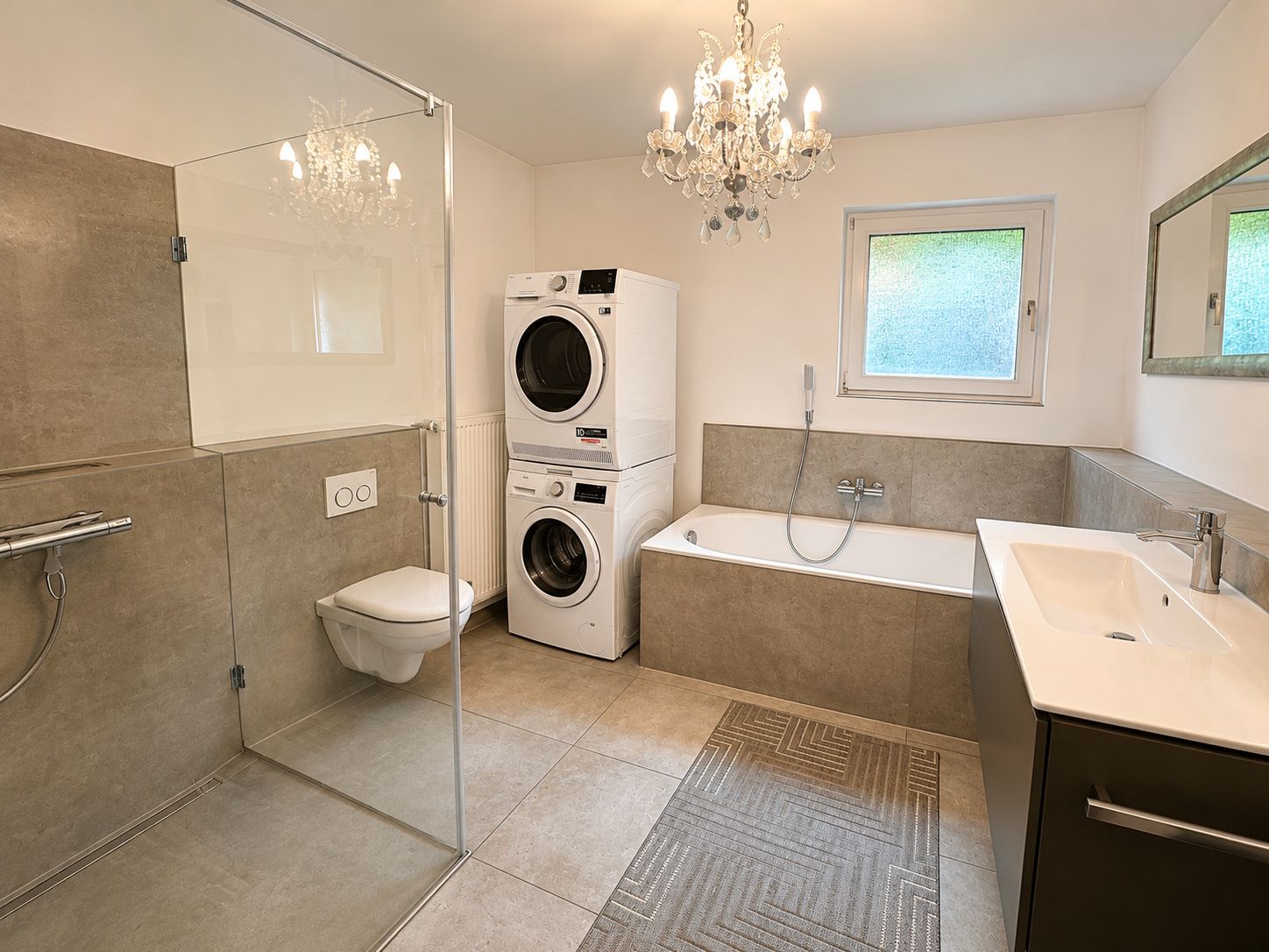 Modernes Badezimmer mit Dusche, Badewanne, Waschmaschine, Trockner und Kronleuchter.