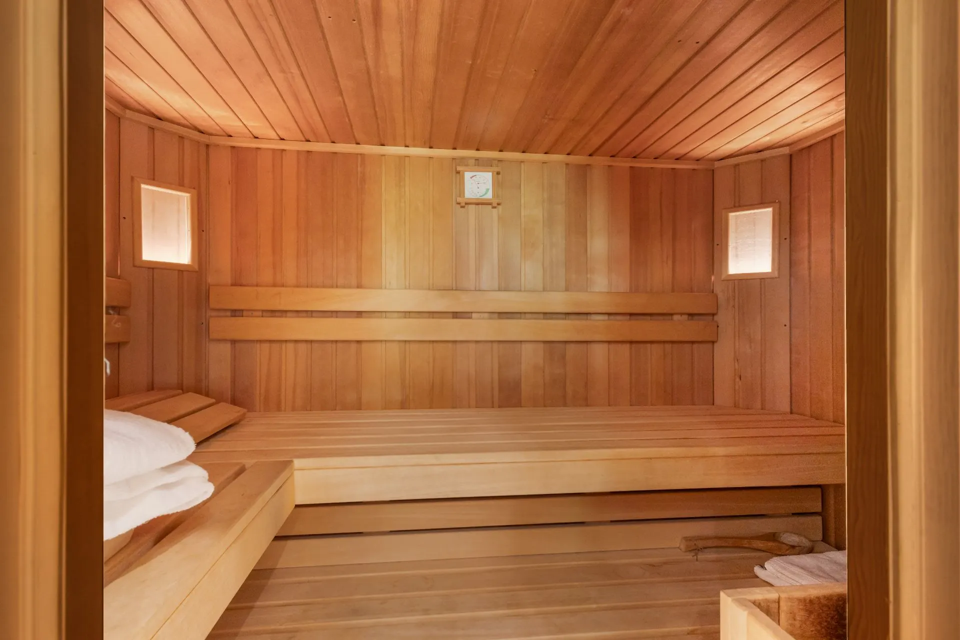 Innenansicht einer Holzsauna mit zwei Bänken und Handtüchern.