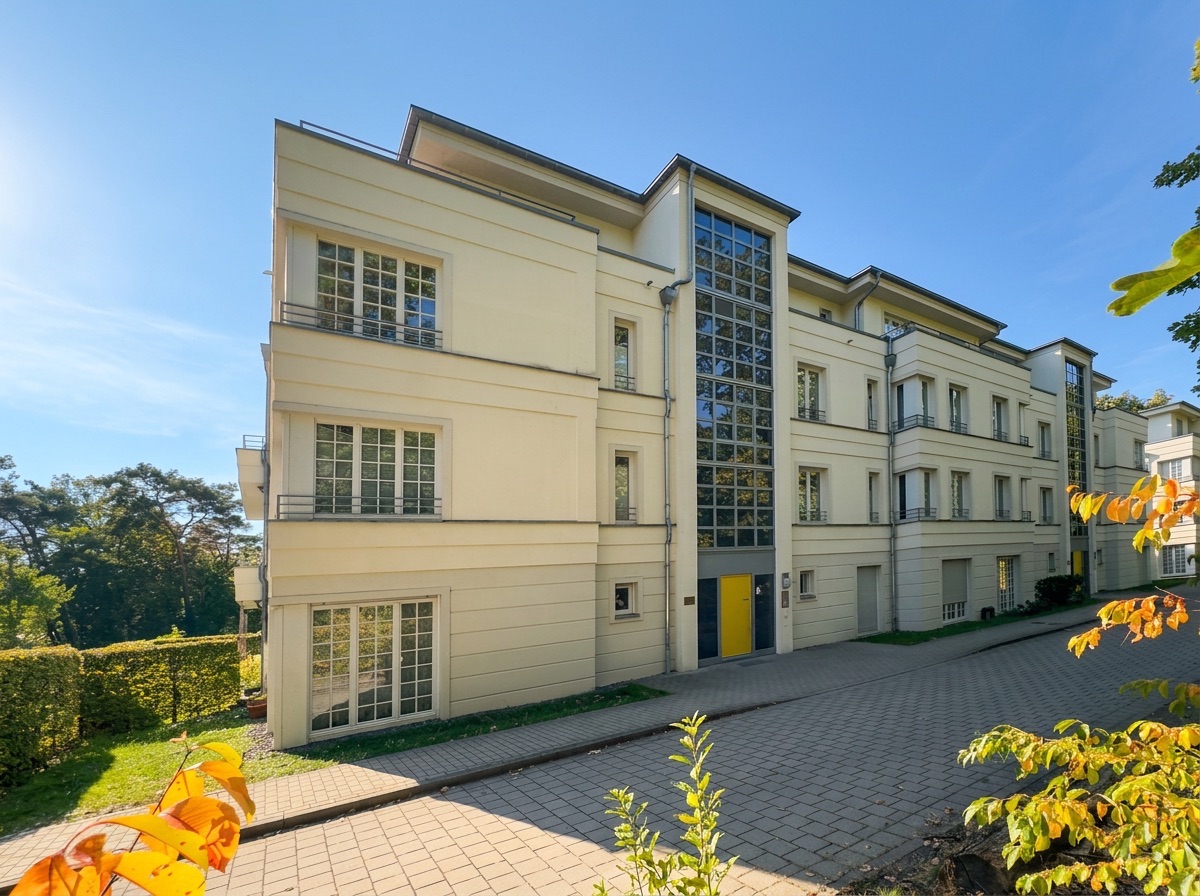 Modernes, mehrstöckiges Wohngebäude mit gelber Tür und vielen Fenstern am sonnigen Tag.