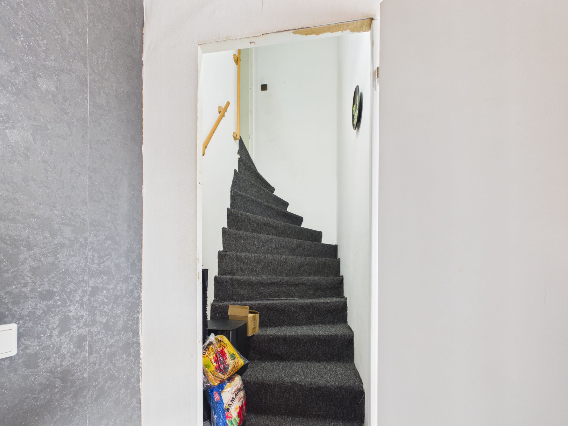 Eine enge, mit Teppich belegte Treppe mit etwas Verpacktem auf der untersten Stufe.