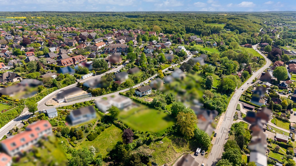 Luftaufnahme eines Wohngebiets mit vielen Häusern, Straßen und viel Grün.