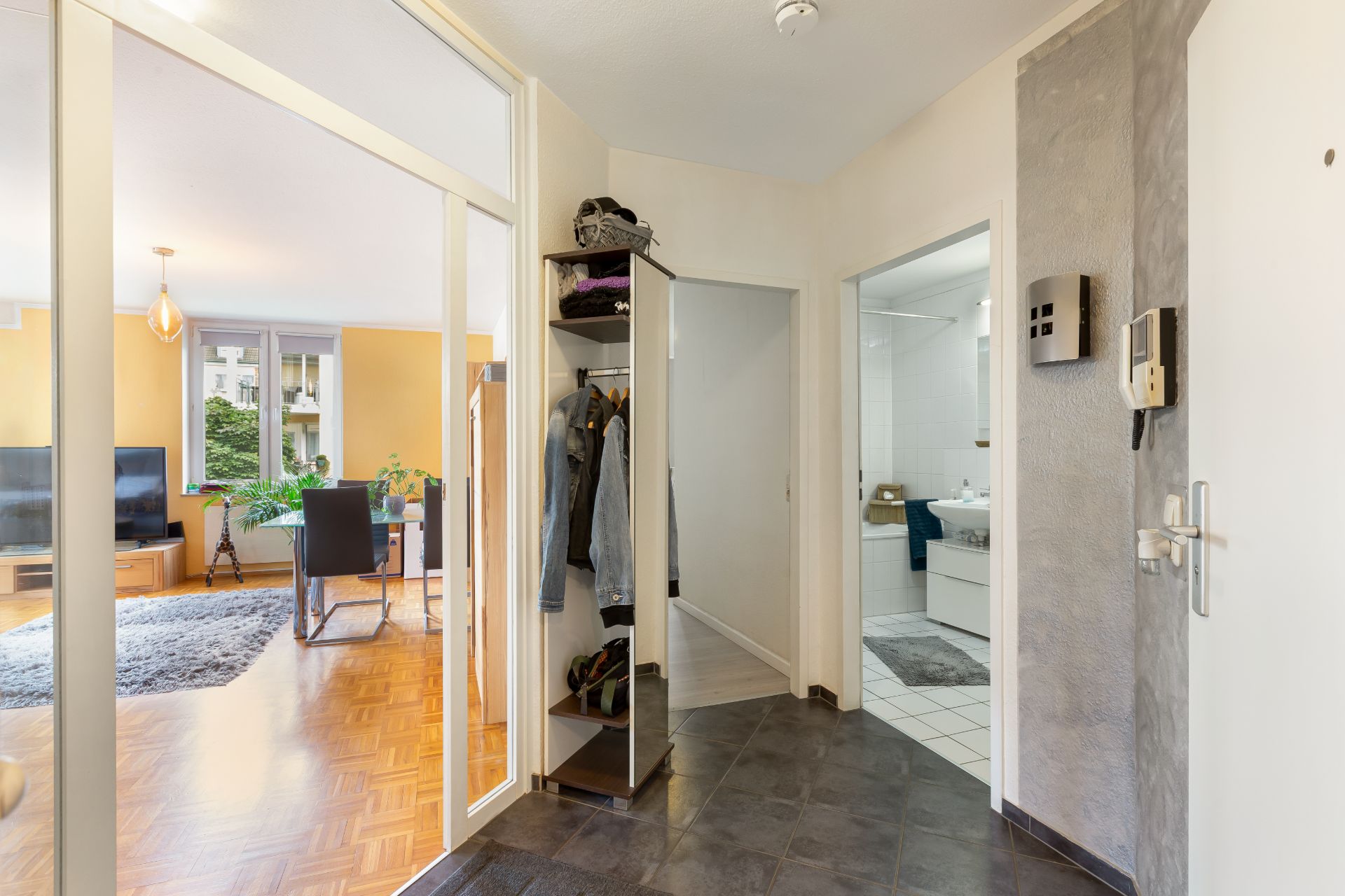 Heller Flur mit Garderobe, Blick ins Wohnzimmer und ins Badezimmer.
