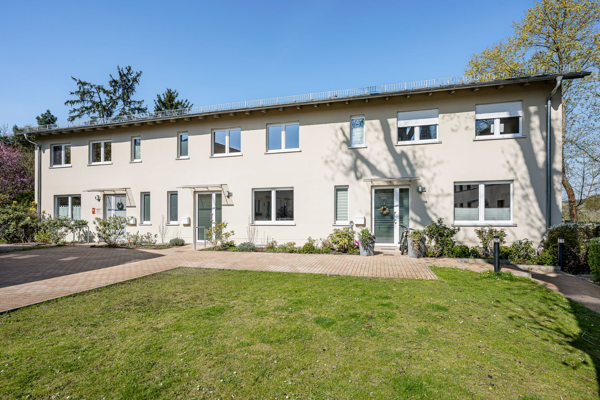 Zweistöckiges Wohnhaus mit mehreren Eingängen und gepflegtem Vorgarten.