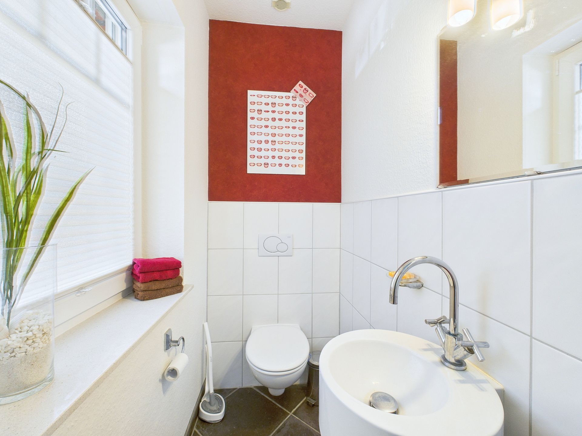 Kleines Bad mit Toilette, rundem Waschbecken und Fenster mit Pflanze auf der Fensterbank.