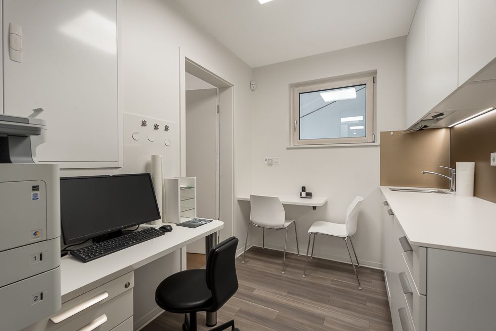 Modernes, kleines Arbeitszimmer mit Schreibtisch, Computer, Stühlen und Küchenzeile.