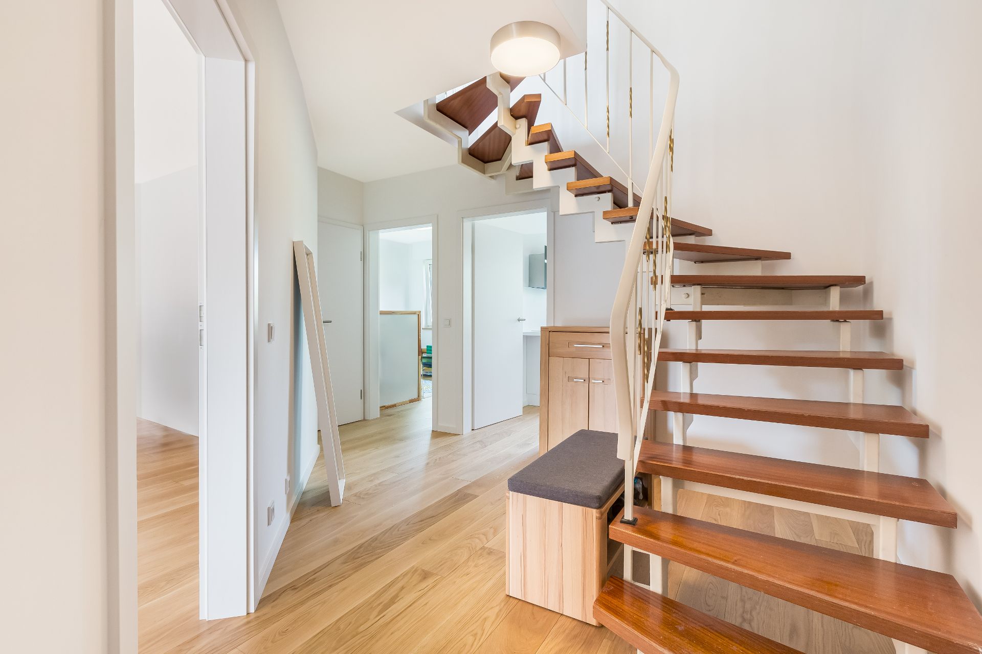 Heller Flur mit Holztreppe, Holzbank, Türen zu weiteren Zimmern und einem Spiegel an der Wand.