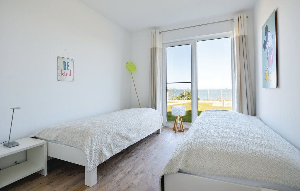 Helles Schlafzimmer mit zwei Einzelbetten, Nachttisch, großem Fenster und Blick aufs Meer.