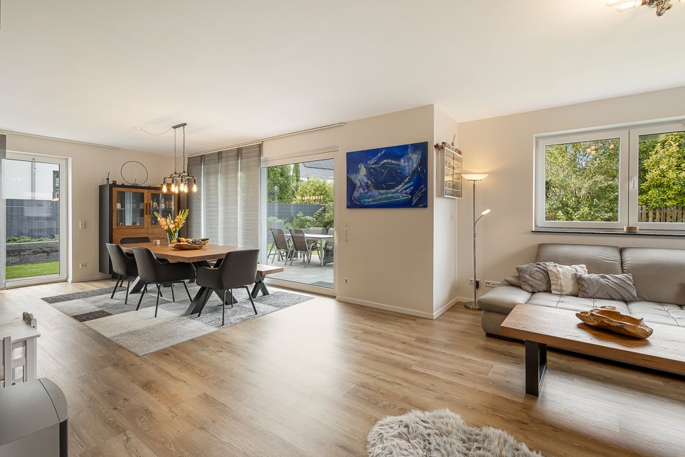 Modernes Wohnzimmer mit Essbereich, großem Fenster und Zugang zur Terrasse.