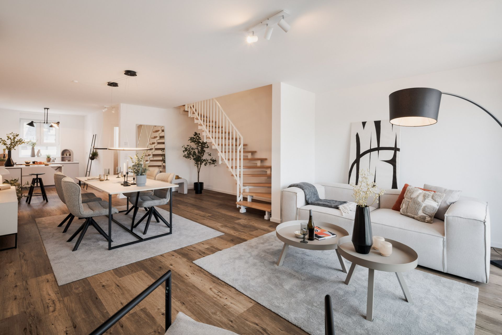 Modernes Wohnzimmer mit Essbereich, Treppe, Holzboden und heller Einrichtung.