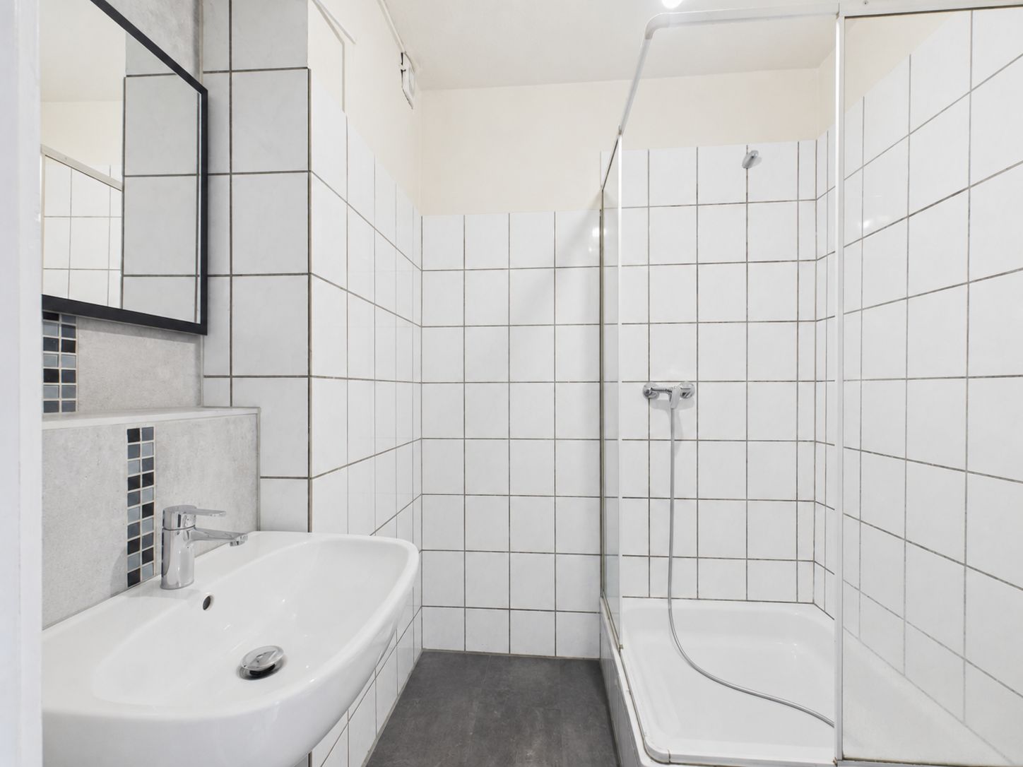 Modernes Badezimmer mit weiß gefliester Dusche, Waschbecken und Spiegel.