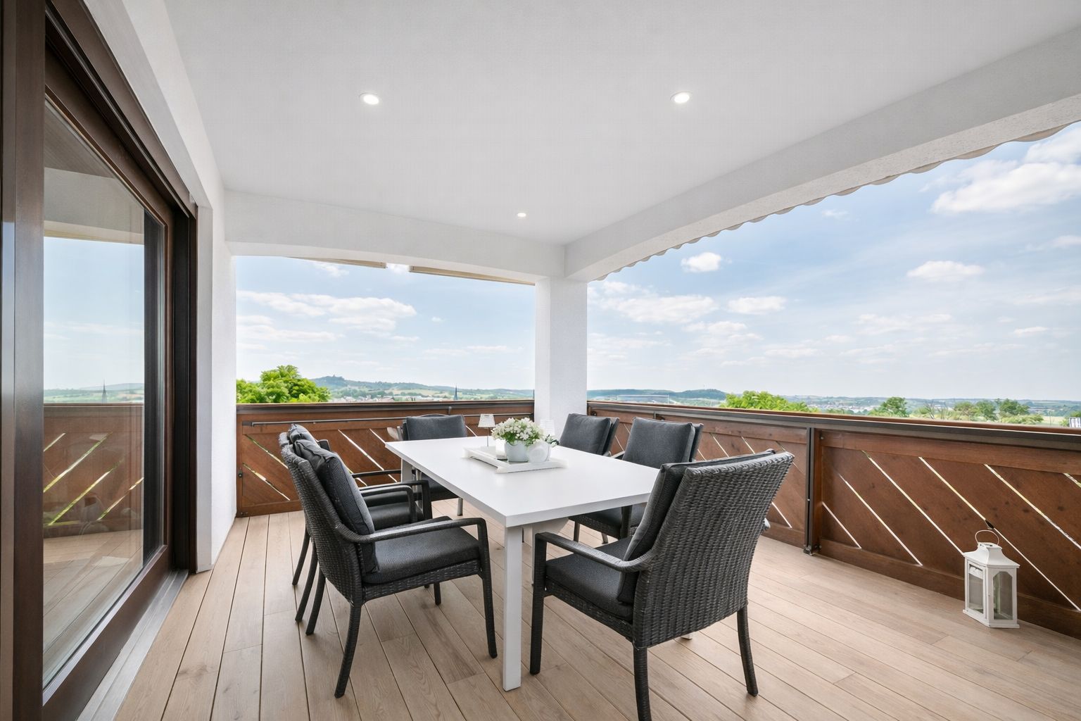 Überdachte Terrasse mit Esstisch, sechs Stühlen und Ausblick ins Grüne.