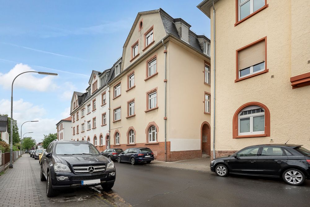 Wohngebäude mit mehreren Stockwerken an einer Straße mit parkenden Autos.