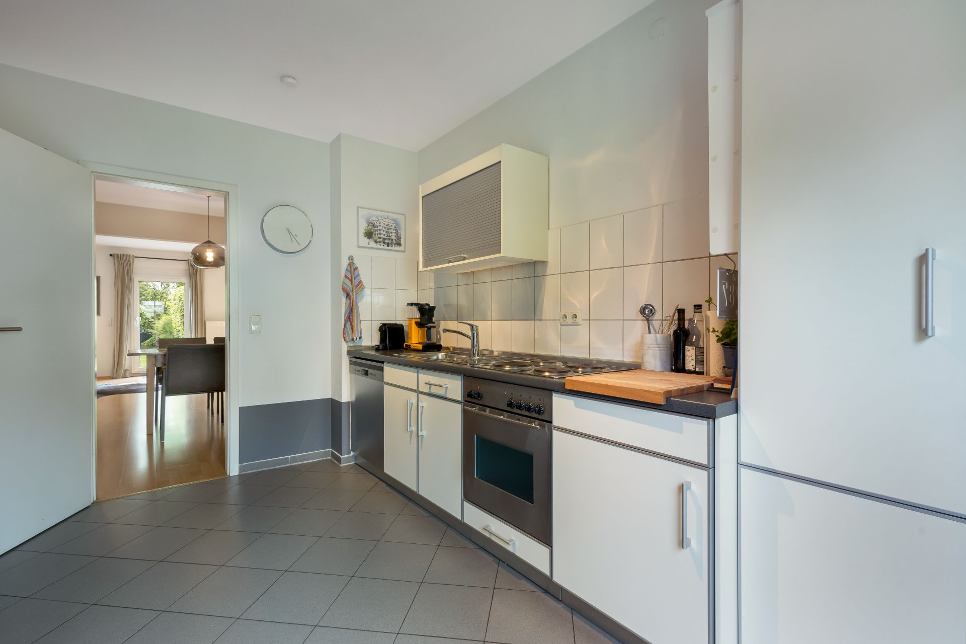 Moderne Einbauküche mit Herd, Backofen und Küchenutensilien, Blick ins Esszimmer.