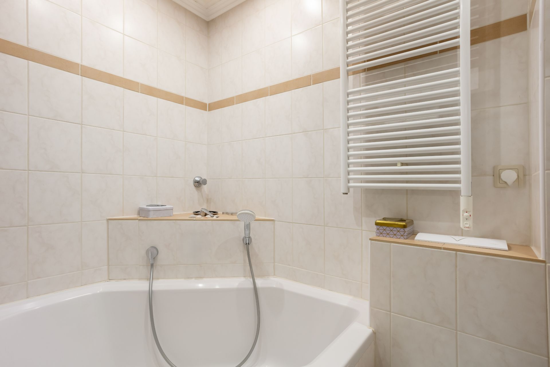 Modernes Badezimmer mit Eckbadewanne, weißen Fliesen und Handtuchheizkörper.