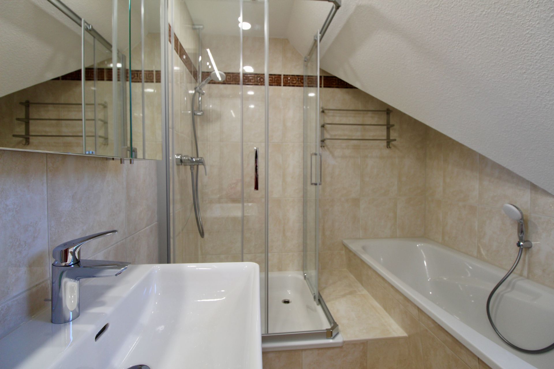 Modernes Bad mit Waschbecken, Dusche, Badewanne und Schräge.