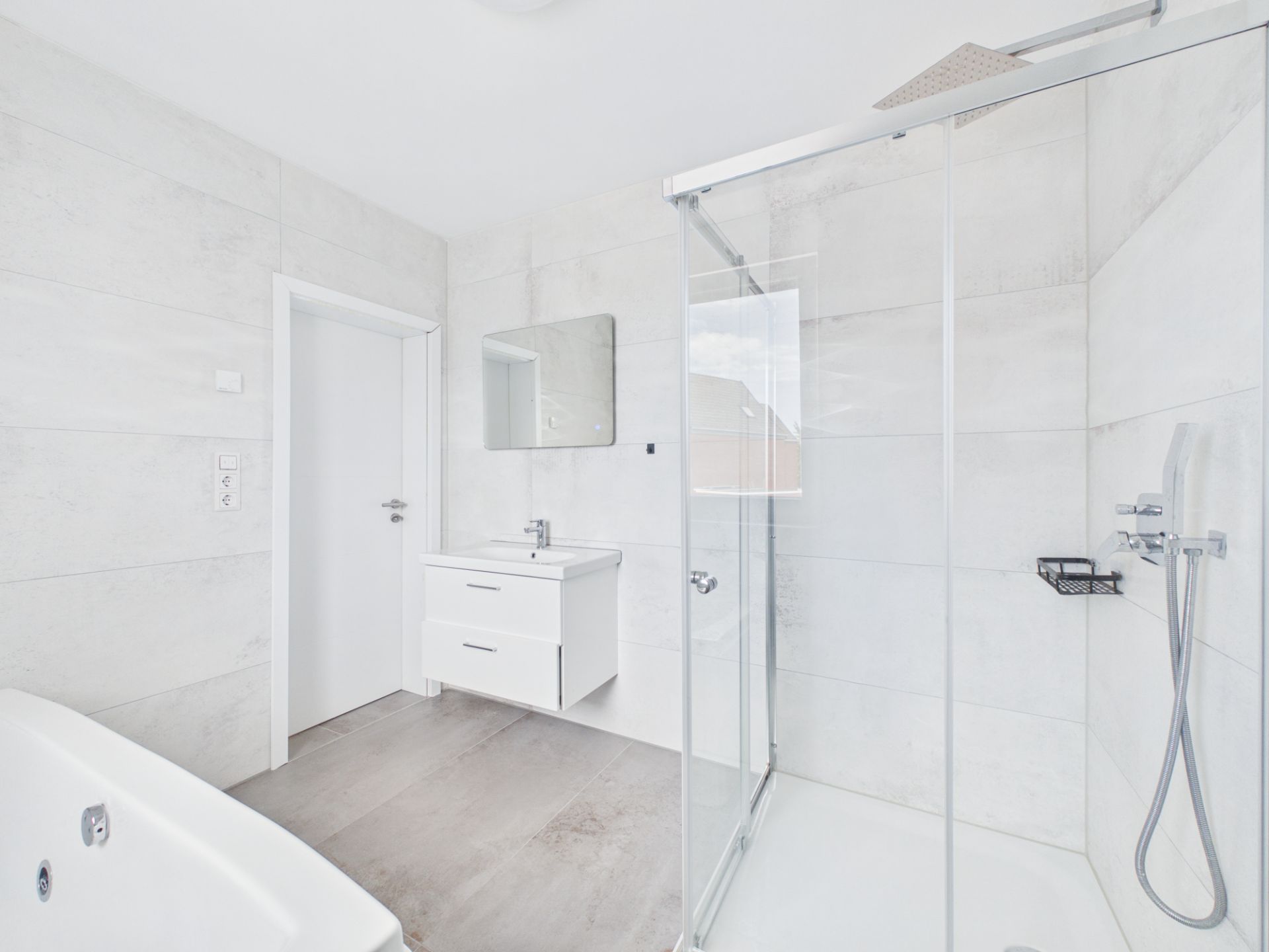 Helles Badezimmer mit Dusche, Badewanne, Waschbecken und Spiegel.
