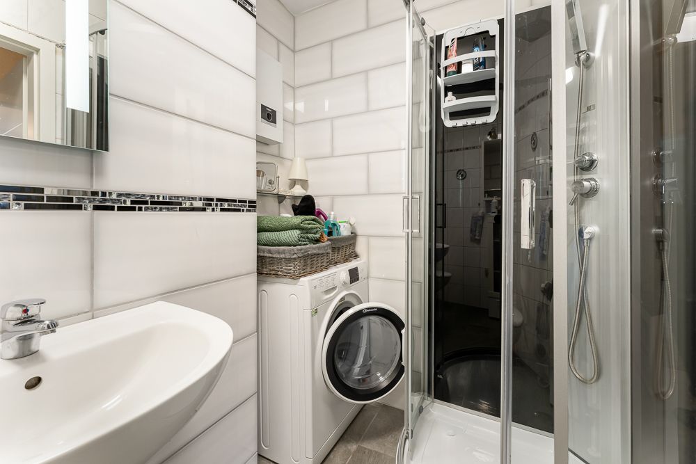 Kleines Badezimmer mit Waschbecken, Waschmaschine und Duschkabine.