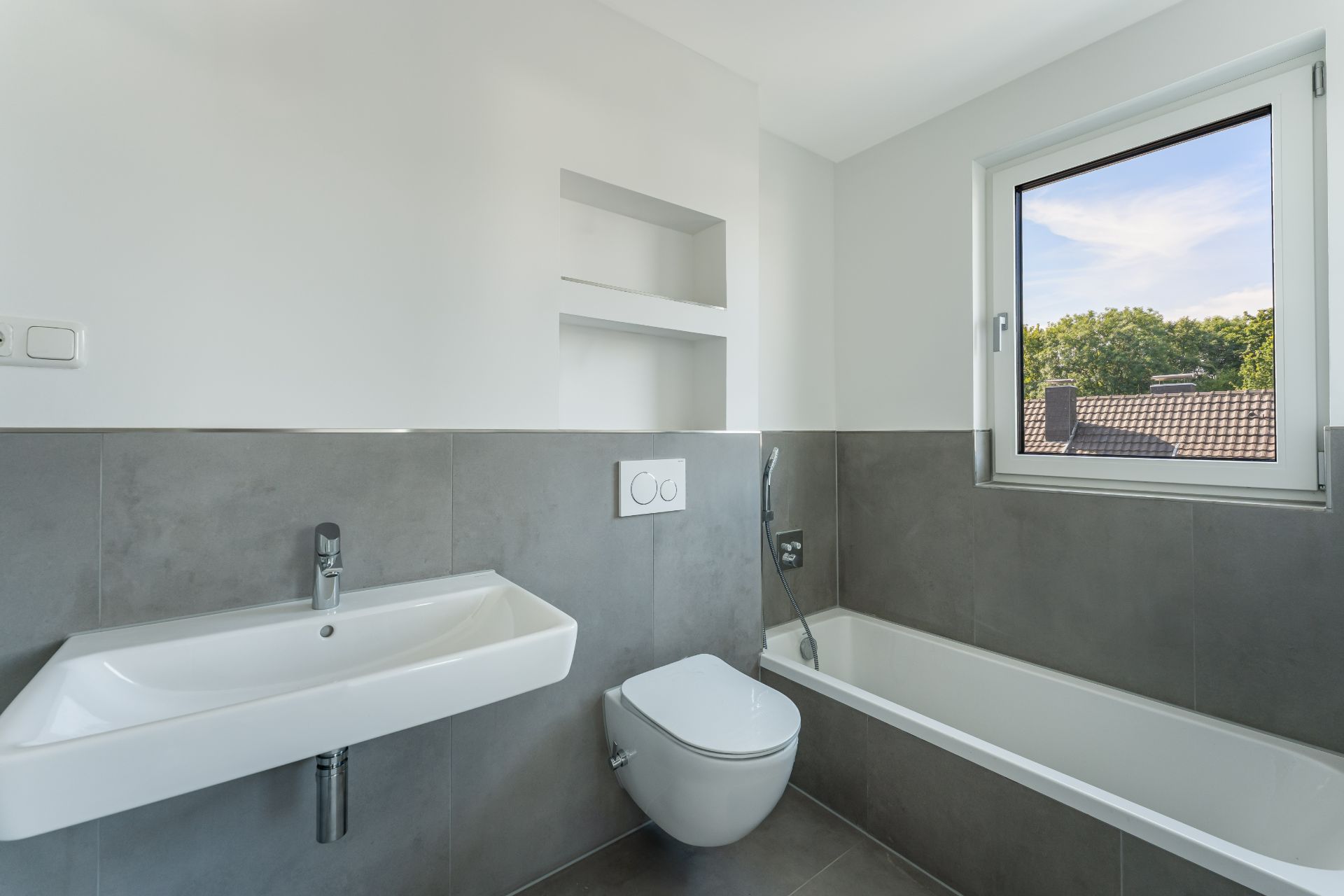 Modernes Badezimmer mit Waschbecken, Toilette, Badewanne und Fenster.