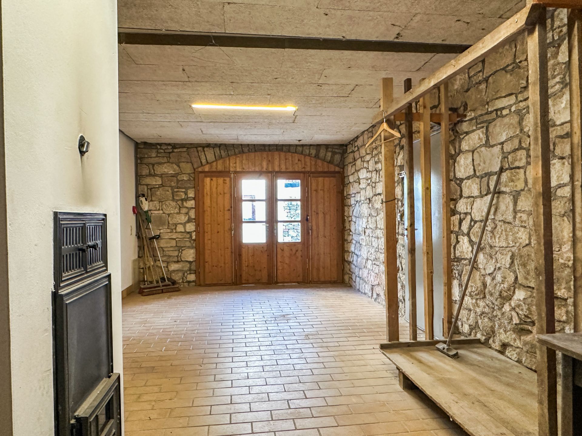 Raum mit Steinwänden, Fliesenboden und Holztür mit Glasfenstern.
