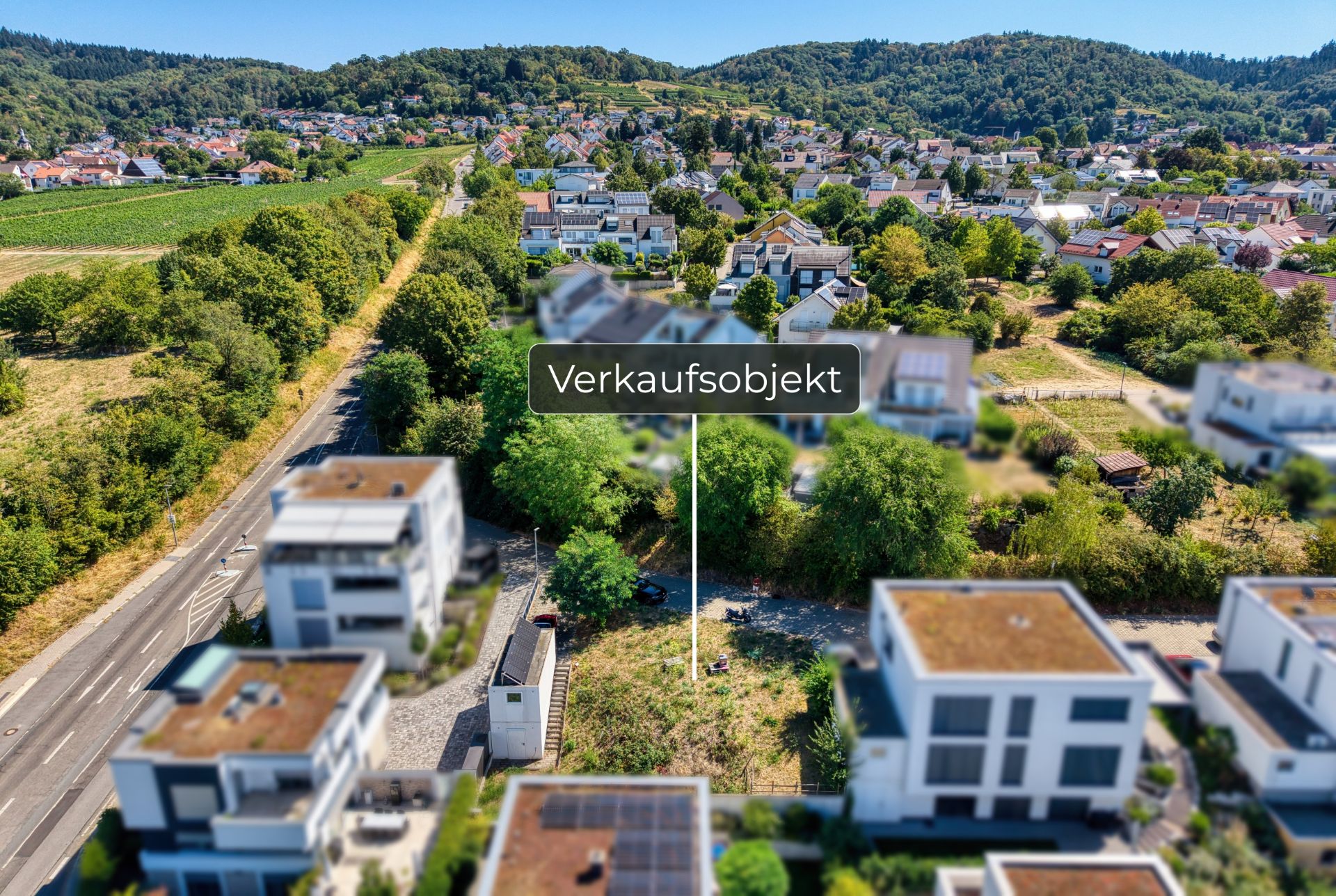 Luftaufnahme eines zu verkaufenden Grundstücks inmitten einer Wohnsiedlung mit moderner Bebauung.