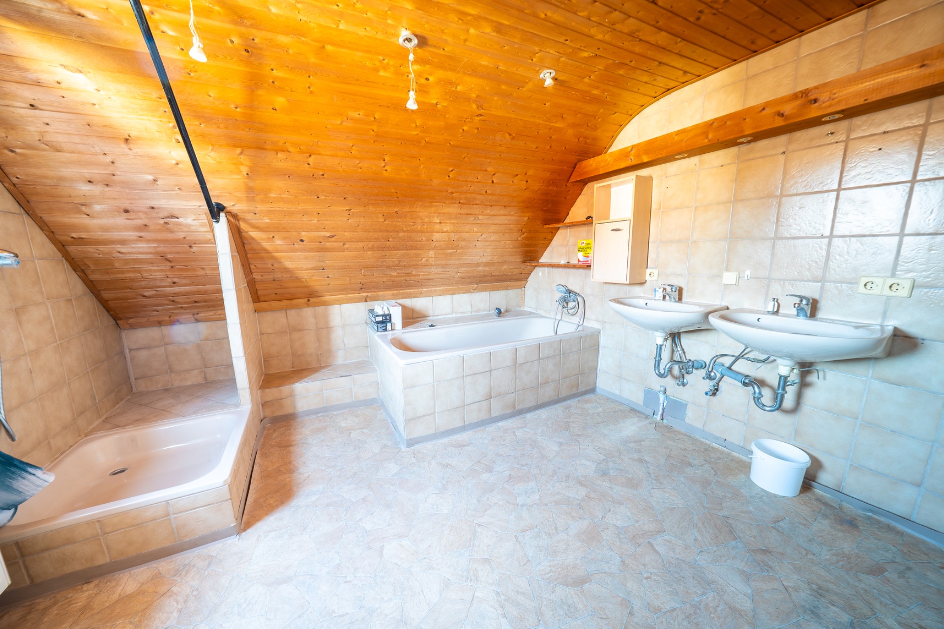 Großes Badezimmer mit Eckbadewanne, Dusche, zwei Waschbecken und Holzdecke.