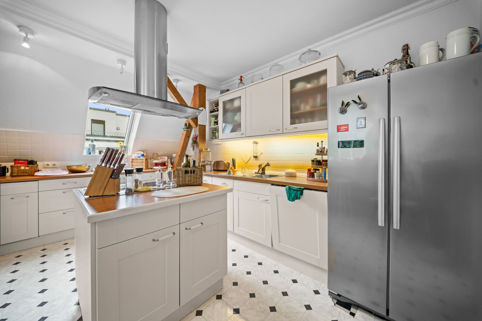Helle Küche mit Kücheninsel, großem Kühlschrank und weißen Schränken.