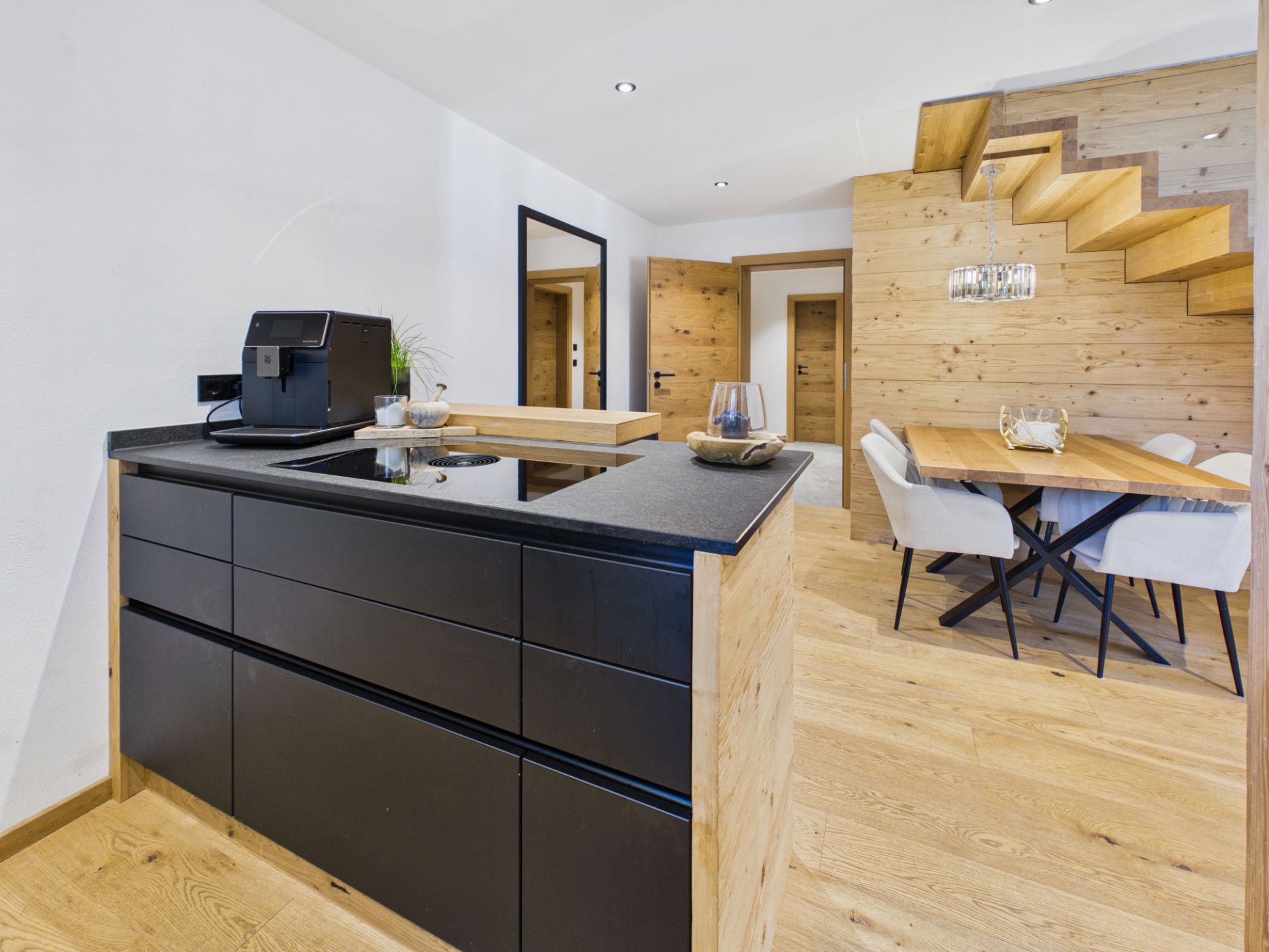 Moderne Küche mit schwarzer Arbeitsplatte, Esstisch und Treppe in einem offenen Wohnraum.