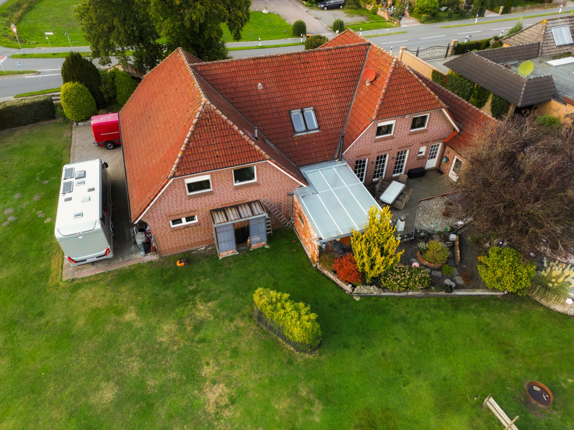 Luftaufnahme eines Backsteinhauses mit rotem Dach und großem Garten.