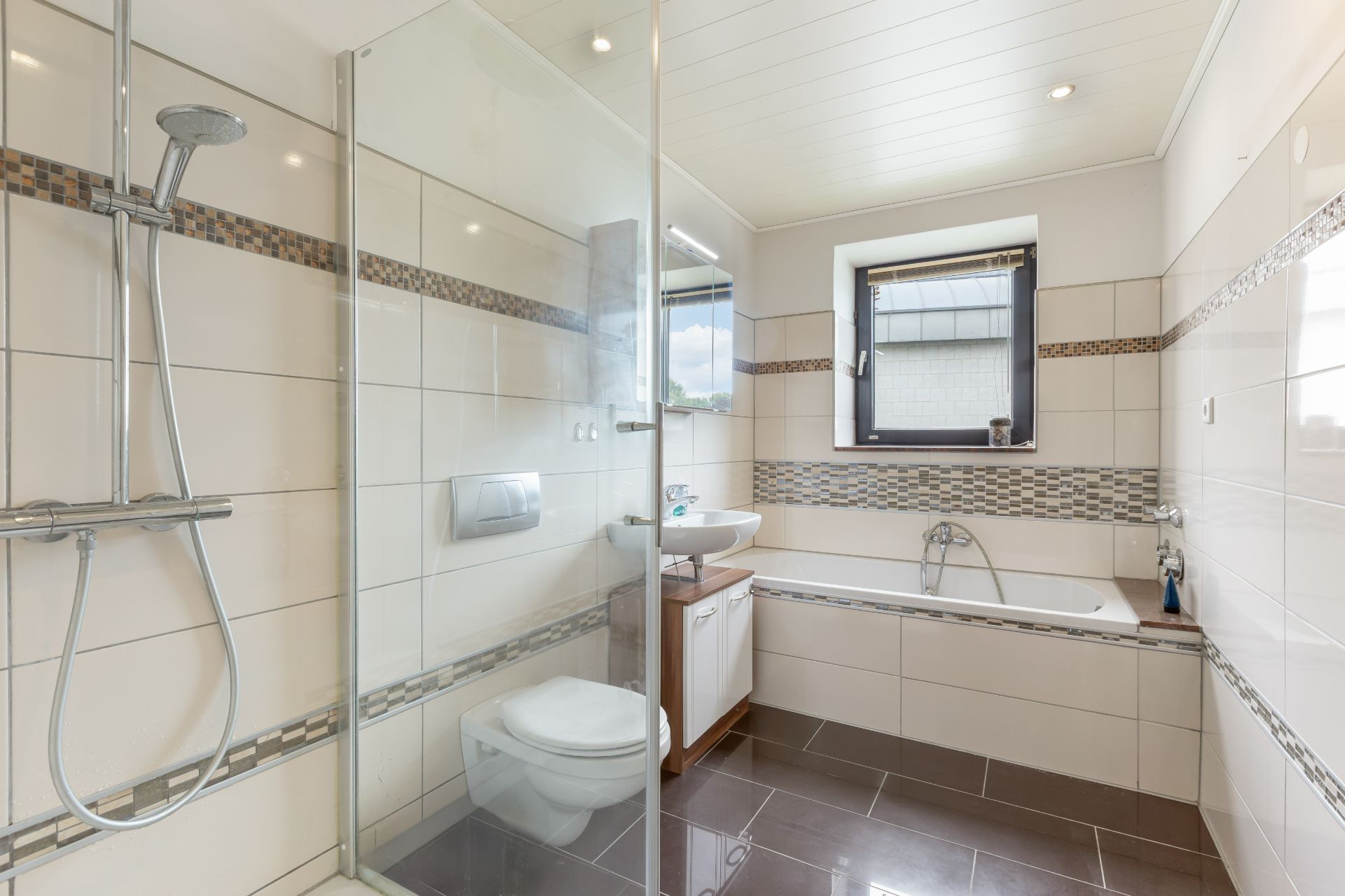 Modernes Badezimmer mit Dusche, Badewanne, WC und Fenster.
