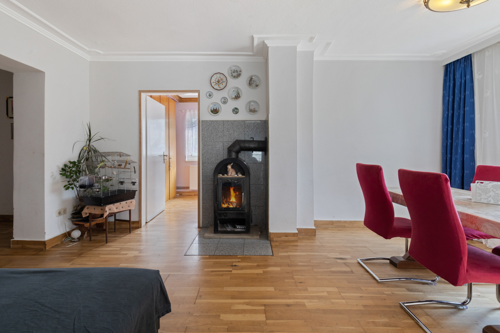 Wohnzimmer mit Kamin, rotem Esstisch mit Stühlen und Vogelkäfig auf Holzfußboden.