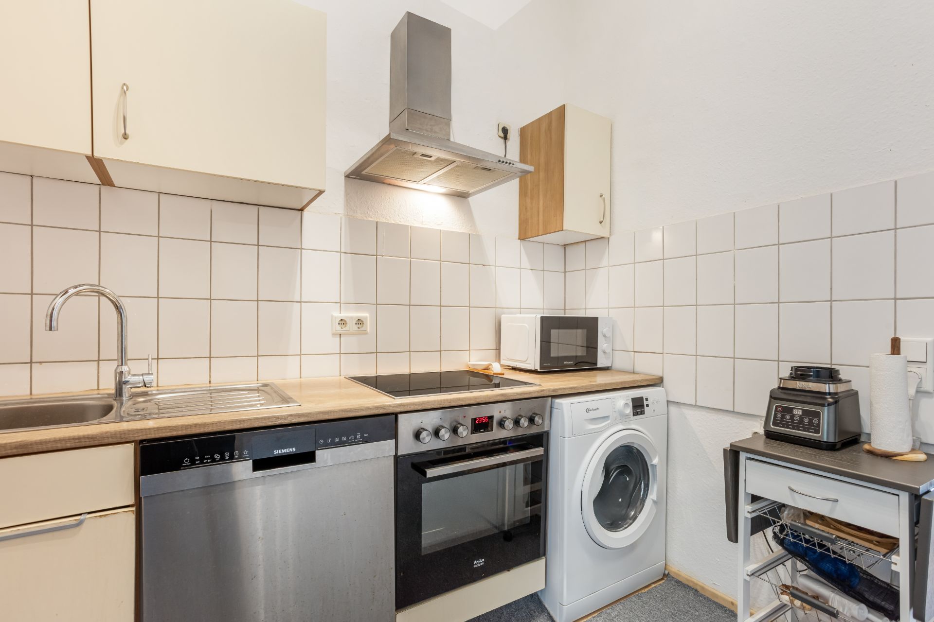 Moderne Küche mit Spüle, Geschirrspüler, Herd, Backofen, Waschmaschine und Mikrowelle.