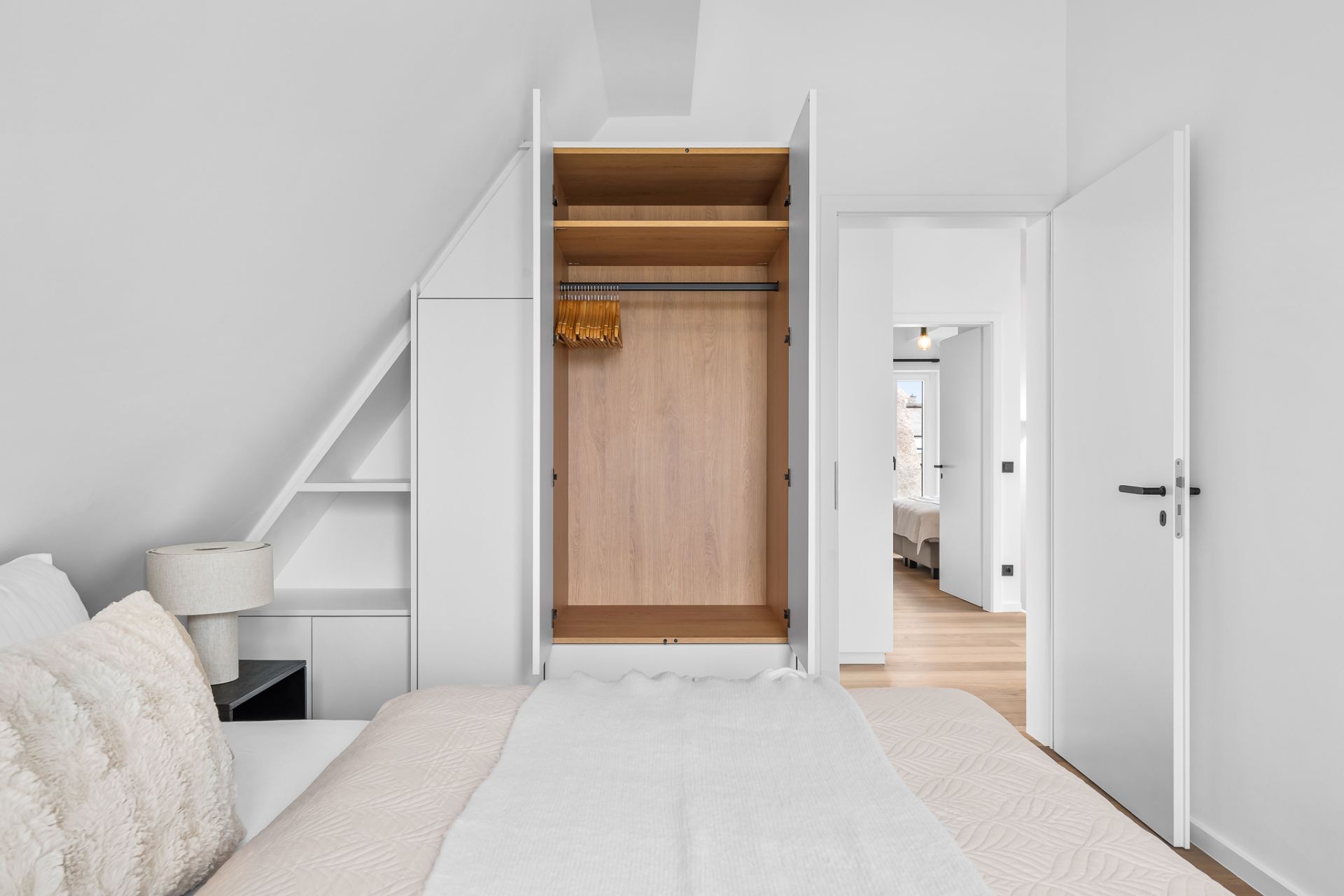 Modernes Schlafzimmer mit offenem Kleiderschrank, Bett und Nachttischlampe.