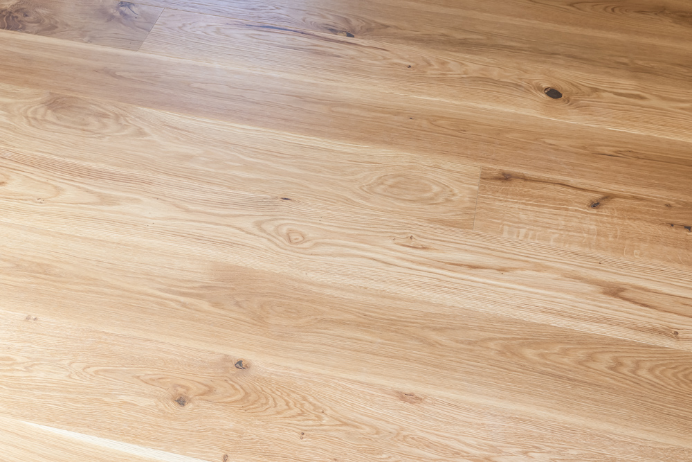 Heller Holzboden mit sichtbarer Maserung und natürlichen Ästen.