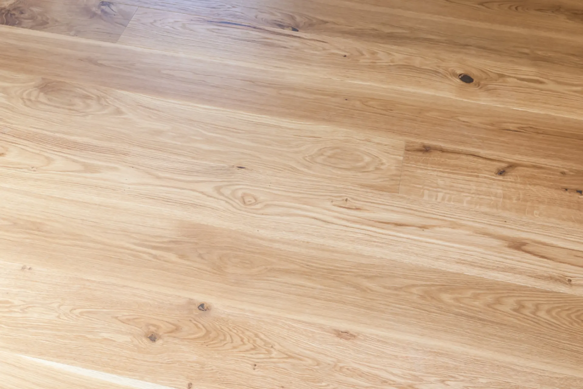 Heller Holzboden mit sichtbarer Maserung und natürlichen Ästen.