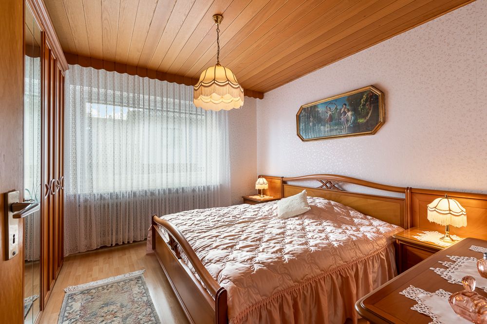 Helles Schlafzimmer mit Holzdecke, großem Bett, Nachttischen und Kleiderschrank.