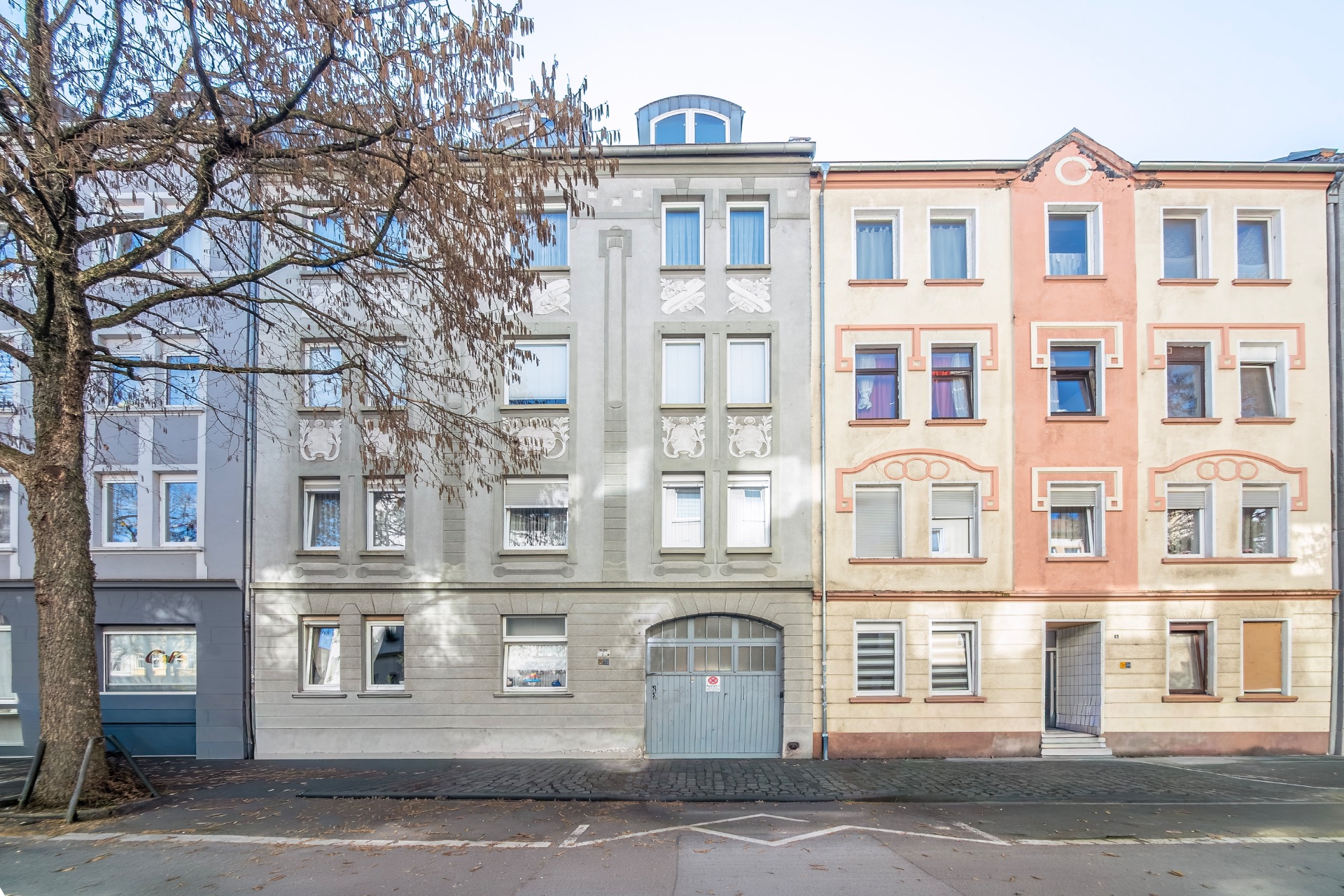 Vorderansicht von zwei mehrstöckigen Wohnhäusern mit Fenstern und Türen an einer Straße.