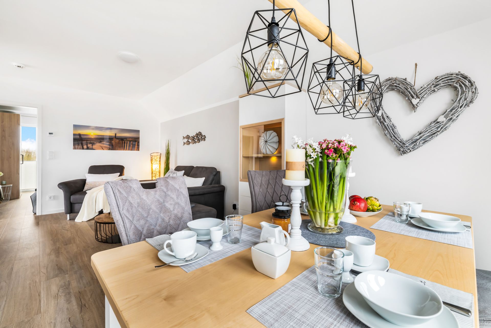Heller Essbereich mit gedecktem Holztisch, modernen Lampen und Blick ins Wohnzimmer.